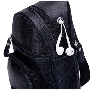 Detalle del bolso de pecho en cuero negro con puerto de auriculares y cremalleras metálicas