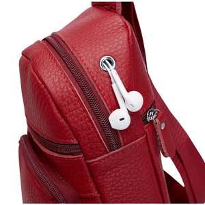 Detalle del bolso de pecho en cuero rojo con puerto para auriculares y cremallera plateada