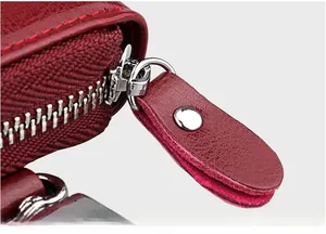 Macro detail of red lychee leather car key case featuring smooth silver metal zipper