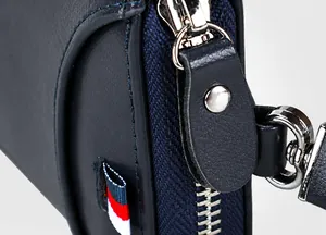 Detalle de cremallera plateada y cinta tricolor en el estuche de llaves de cuero azul