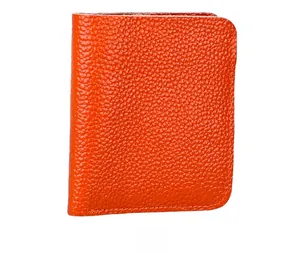 Close-up of bright orange litchi grain leather texture on minimalist short wallet