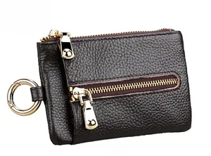 Macro shot of dark brown pebbled leather texture and three gold metal zippers on key pouch