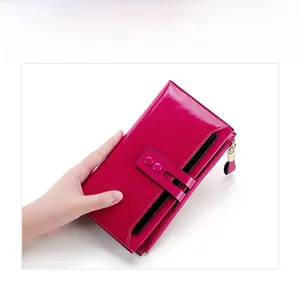 Detail view of glossy magenta leather wallet with gold zipper and stylish rivet strap