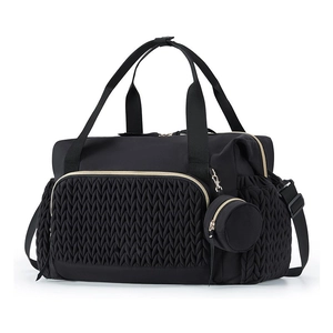 Detail of black waterproof diaper bag with woven quilted front pocket and gold zippers