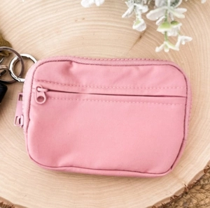 Pink waterproof nylon coin purse with a metal keychain displayed on a wood tray