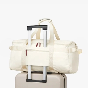 Close-up of the rear luggage sleeve on a cream travel bag attached to a suitcase handle