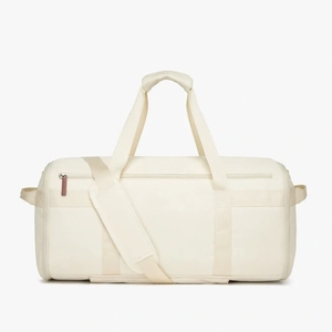 Detail of cream travel bag showing padded shoulder strap and durable nylon texture