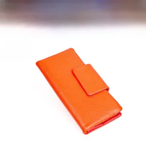 Detail view of a minimalist orange leather wallet with premium litchi texture and magnetic snap