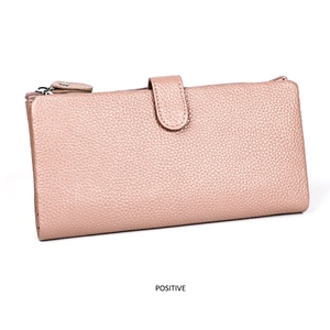 Macro shot of litchi grain cowhide leather and decorative metal buckle on a pink wallet