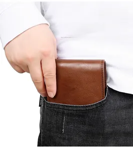 Short brown leather bifold wallet being placed into the back pocket of denim jeans