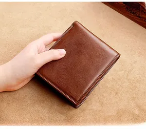 Short brown genuine leather bifold wallet held in hand showing realistic size and texture