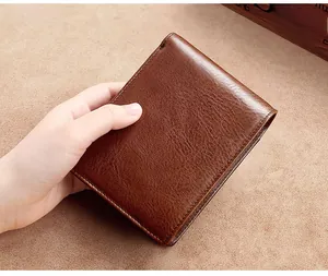 Close-up of brown genuine leather men's wallet showing natural grain texture and hand-held view