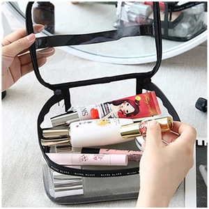 Mano che inserisce prodotti di bellezza in una trousse trasparente in PVC con bordi neri
