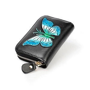 Macro detail of a 3D embossed butterfly on black leather wallet with a gold zipper