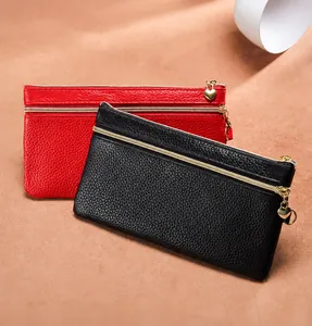 Detail van rode en zwarte litchi lederen clutch met dubbele gouden ritsen en hartjes