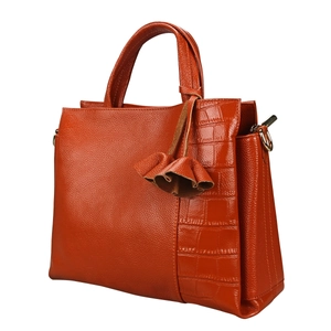 Detail of orange pebble leather handbag with crocodile pattern panel and ruffle charm