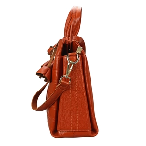 Close-up of orange leather handbag side view showing accordion structure and gold buckles