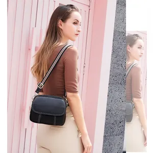 Detail of black pebbled leather crossbody bag with striped strap and white contrast stitching
