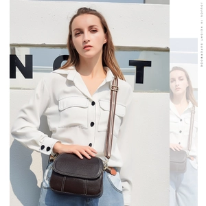 Detail of dark brown lychee grain leather crossbody bag with vintage striped strap