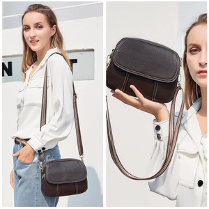 Detail of dark brown lychee grain leather crossbody bag with striped fabric strap