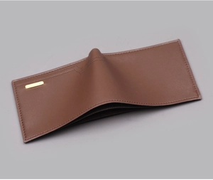 Close-up of a men's bi-fold brown leather wallet featuring fine lychee texture and metal plaque