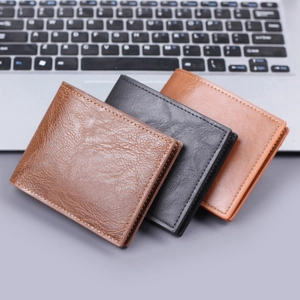 Men's vintage leather bi-fold wallets in brown and black on a laptop keyboard