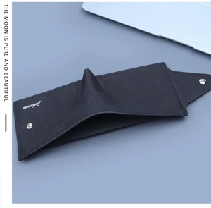 Close-up of black canvas trifold wallet with white logo, metal snap, and stitching