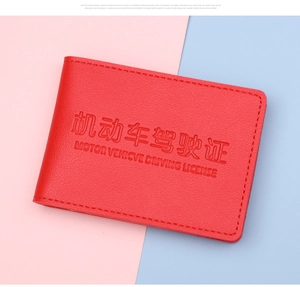 Macro view of red pebbled leather driving license cover with embossed gold lettering