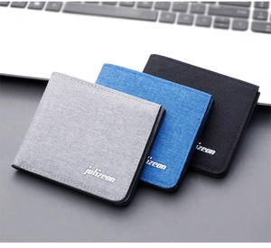 Detailed view of three minimalist canvas bi-fold wallets in grey, blue, and black