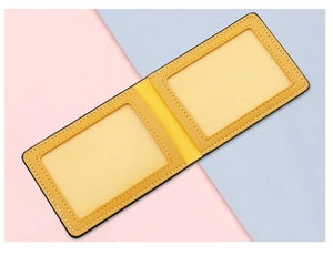 Détail d'un porte-cartes en cuir jaune avec deux fenêtres ID transparentes et surpiqûres