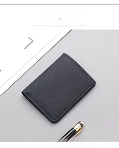 Slim black canvas vertical wallet for men with sleek pen on a minimalist grey background