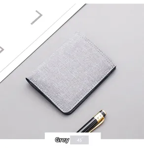Close-up of a minimalist grey canvas vertical wallet with precise stitching and a metal pen