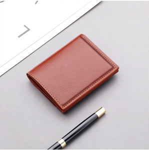 Detailed texture of slim brown leather men's wallet with pen on business desk