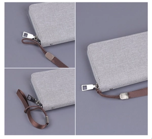 Detailed view of gray canvas clutch with metal zipper and brown wristlet strap