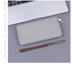 Close-up of grey canvas long clutch with linen texture, wrist strap and zipper detail
