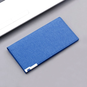 Blue canvas long wallet with denim texture and silver metal corners on a clean grey desk