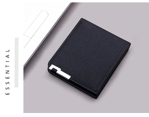 Detail of minimalist black canvas wallet featuring silver metal trim and Essential text