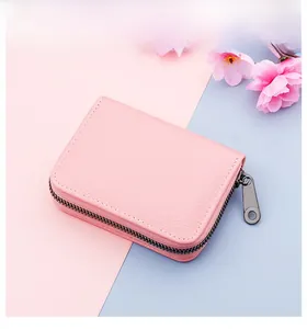 Close-up of pink lychee leather card holder with a metal zipper on a soft pastel background