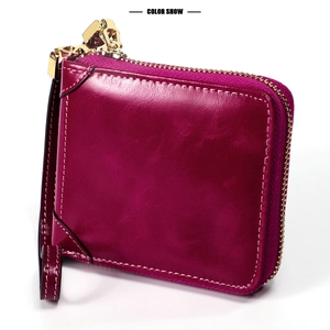 Détail du portefeuille en cuir ciré rose avec zip doré et dragonne de poignet
