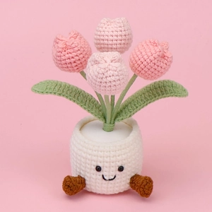 Detail of handmade crochet pink tulip plant in white pot with cute smiley face