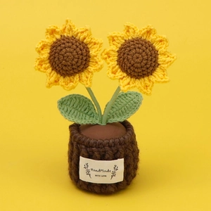 Detail of hand-knitted sunflower plant with HandMade WITH LOVE tag on a yellow background