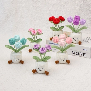 Detail of colorful hand-crocheted tulip potted plants with cute smiling faces on white base