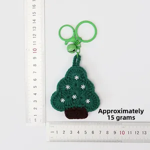 Close-up of handmade crochet Christmas tree keychain with white snowflake and bells