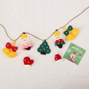 Handcrafted crochet Christmas charms with mini gloves, hats and trees on white fabric