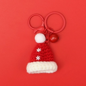 Detail of a handmade knitted Santa hat keychain with snowflake pattern and a small red bell