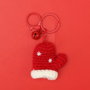 Detail of red crochet mini glove pendant with white snowflakes and festive bell