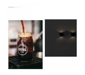 Detail view of a matte black square wall lamp alongside lifestyle coffee elements