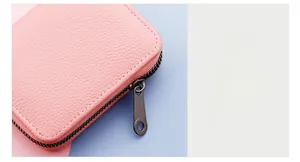 Close-up of pink lychee leather card holder showing durable grey metal zipper detail