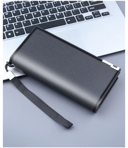 Detail view of black lychee leather clutch bag with silver metal accent on laptop surface