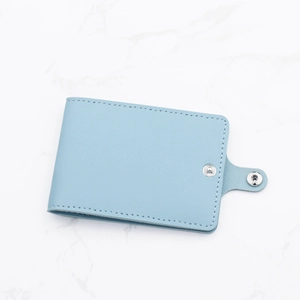 Slim light blue leather card holder with snap button closure on marble background